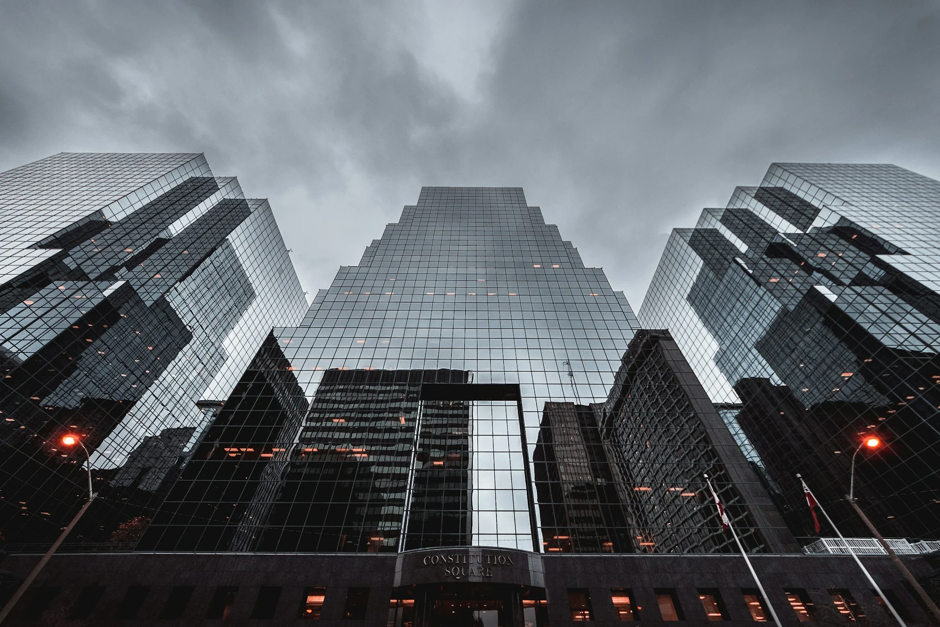 An upward view of glass architecture opening toward the sky.